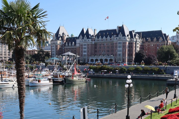 Harbor with boats and a historic building in the background, surrounded by trees and flowers.